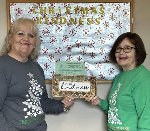 The main two Christmas Kindness office employees, Brenda Povey (left) and Carolyn McNamara (right), hold up a sign that says “Choose Kindness.”