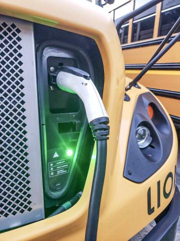 An electric bus connects to a charge port at Three Rivers Public Schools. THREE RIVERS PUBLIC SCHOOL