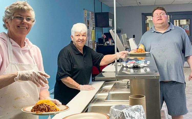 Pictured are Linda Crawford and Dee Jugman serving a meal to Joe Smith.