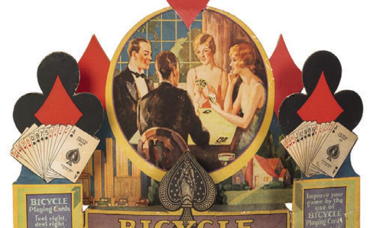 When advertisements include pictures of people, their clothing and hairstyles can help date the item. This store display for Bicycle Playing Cards is from about 1930. KOVELS.COM
