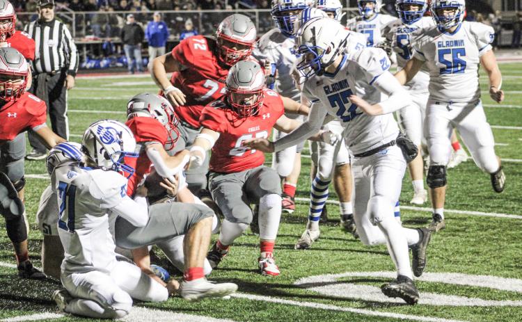 Gladwin’s Talon Goodwin finishes off a gang tackle with Jacob Pahl closing in during the first quarter of Friday night’s 35-0 loss at Frankenmuth in the third round of the Division 5 playoffs.