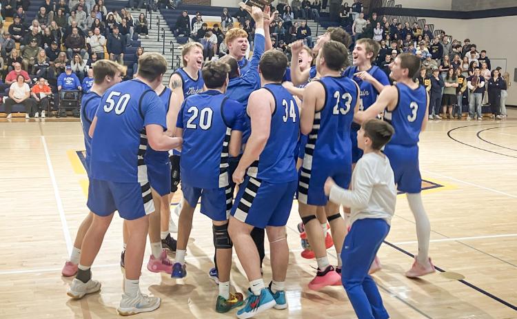 The Gladwin basketball team stormed the court to celebrate with the trophy after winning the Division 2 District Tournament at Shepherd Friday night.