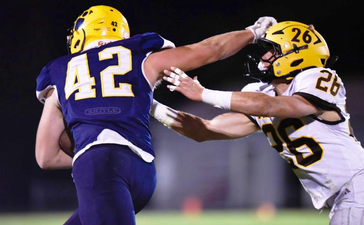 Standish-Sterling’s Rylee Blanchard employs the stiff arm to ward off Ogemaw Heights tackler Lane Winter during the Falcons shutout victory Friday night.