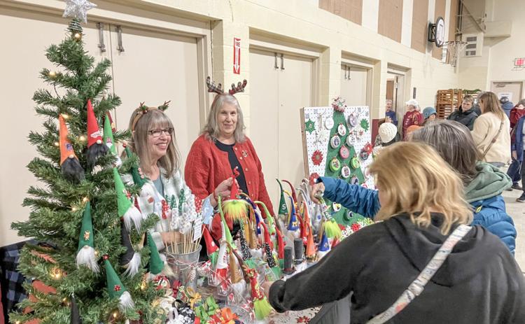 Shoppers check out the Christmas decorations at one of the many colorful booths at the Sacred Heart Bazaar last weekend.