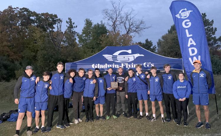 Gladwin’s boys’ cross country team spends some quality time with the Jack Pine Conference trophy after winning a third straight championship Thursday at Harrison.