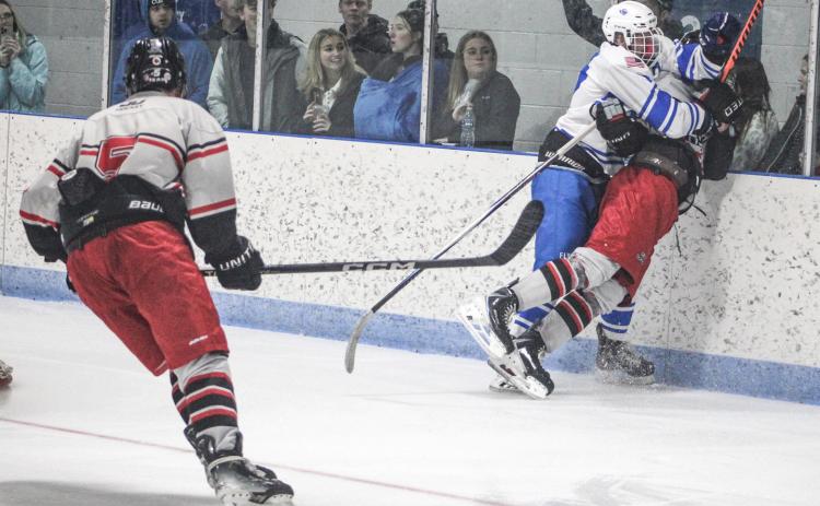 Gladwin’s Hunter Simpson checks in behind the net with a big hit on a Jackson United rival during Saturday’s home opener.