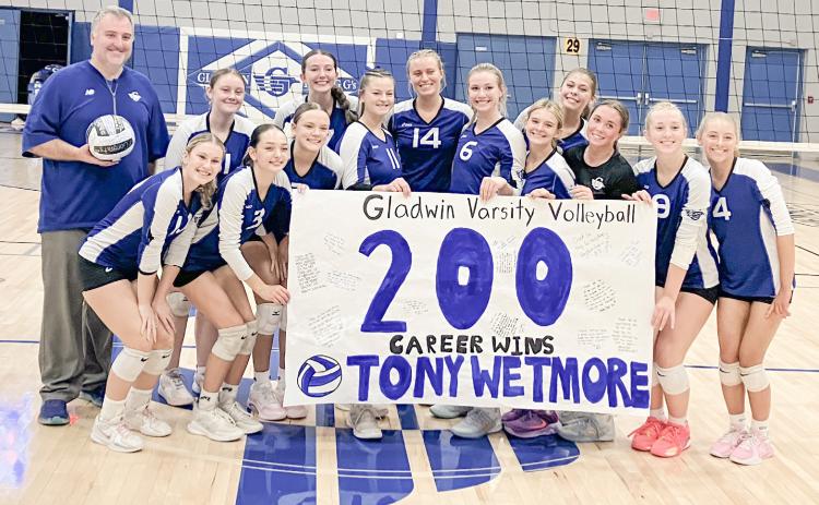 The Gladwin volleyball team celebrates with Coach Tony Wetmore after delivering his 200th career victory last Wednesday by sweeping visiting Standish.