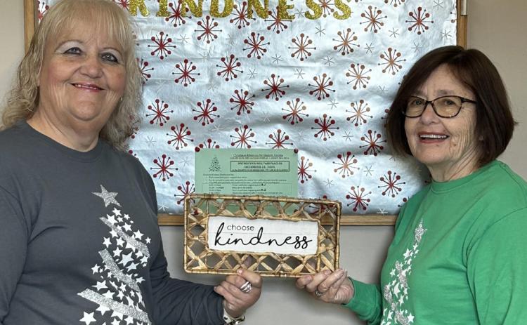 The main two Christmas Kindness office employees, Brenda Povey (left) and Carolyn McNamara (right), hold up a sign that says “Choose Kindness.”
