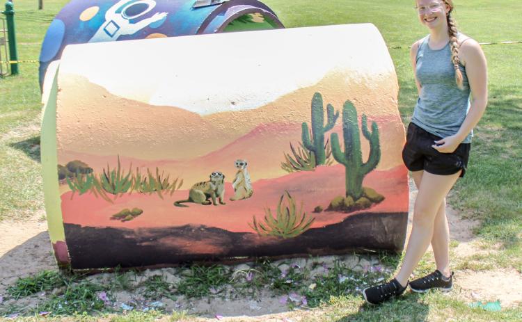 High school student paints City Park playground equipment