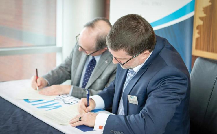 Scott Mertes (Mid) and Sean Burke (Alma), Provosts of their respective institutions, sign the agreement.